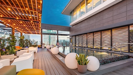 Una piscina al aire libre, sombrillas, sillones reclinables de piscina