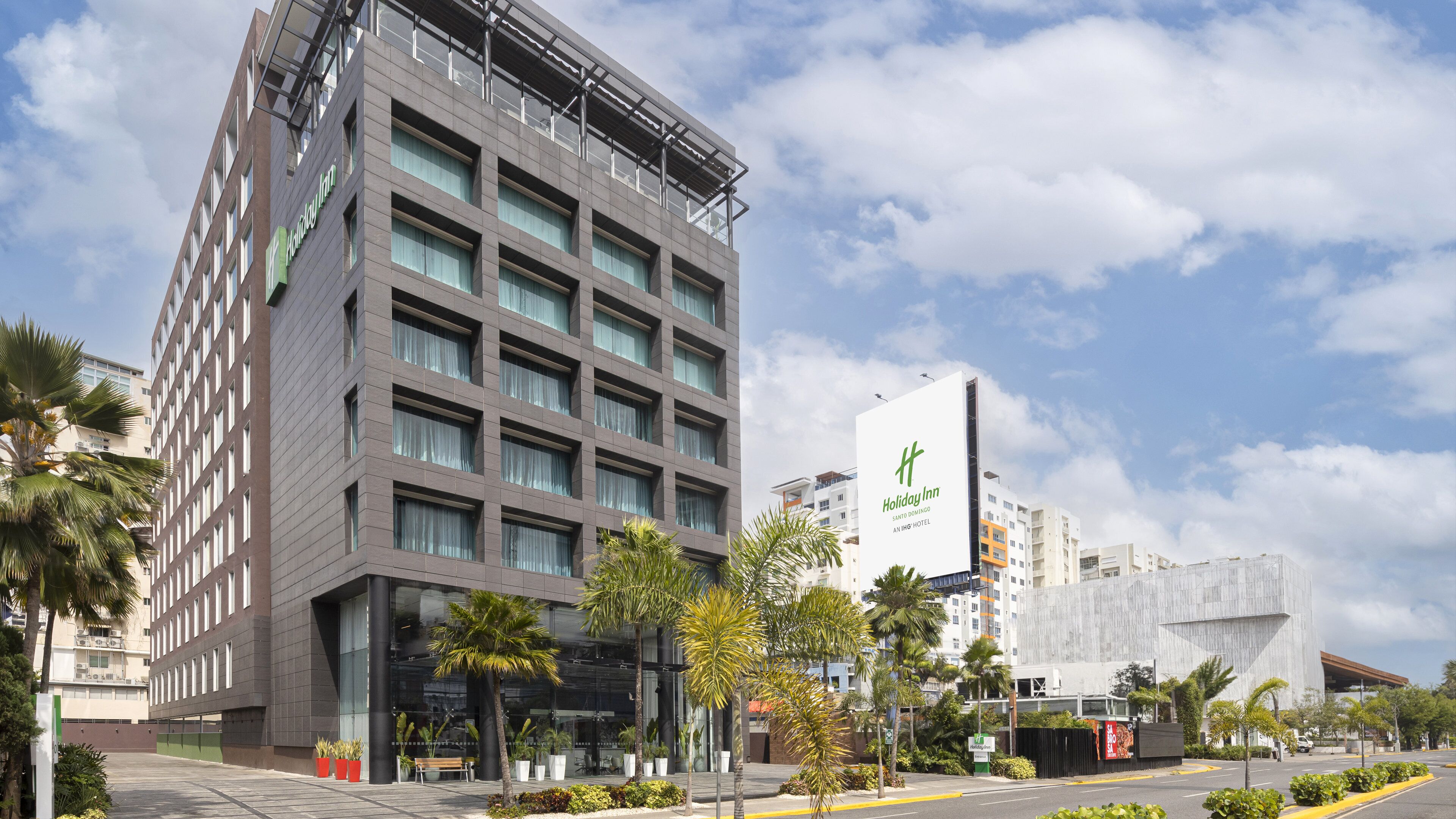 Un moderno edificio de hotel con varios pisos, ventanas amplias y un cartel llamativo de Holiday Inn.