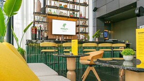 A Holiday Inn lobby with a bar area, seating, and a large screen displaying the hotel name. - Holiday Inn Santo Domingo by IHG (Santo Domingo)