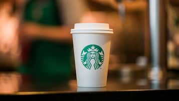 Une tasse Starbucks avec le logo, posée sur un comptoir.