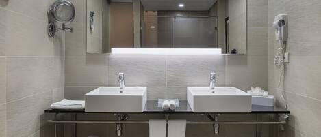 Un baño moderno con dos lavamanos, un espejo grande, un perchero para toallas y un secador de pelo.
