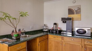 A compact kitchen with a sink, a coffee maker, a microwave, and a small potted plant. - Motel 6 Rossford, OH (Rossford)