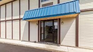 A building with a blue awning, a glass door entrance, and a 'No Smoking' sign. - Motel 6 Rossford, OH (Rossford)