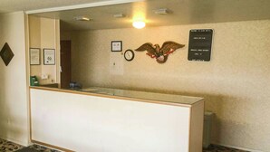 Un mostrador de recepción con un reloj, un cartel en la pared y un emblema decorativo de águila.