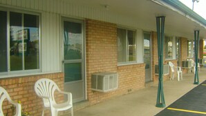 Un motel con fachada de ladrillo, ventanas amplias y sillas exteriores.