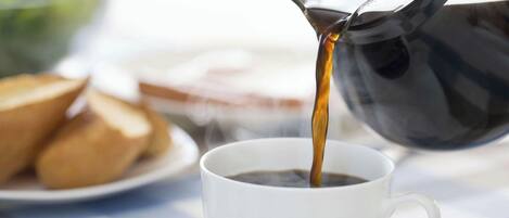 Se vierte café de una cafetera negra.
