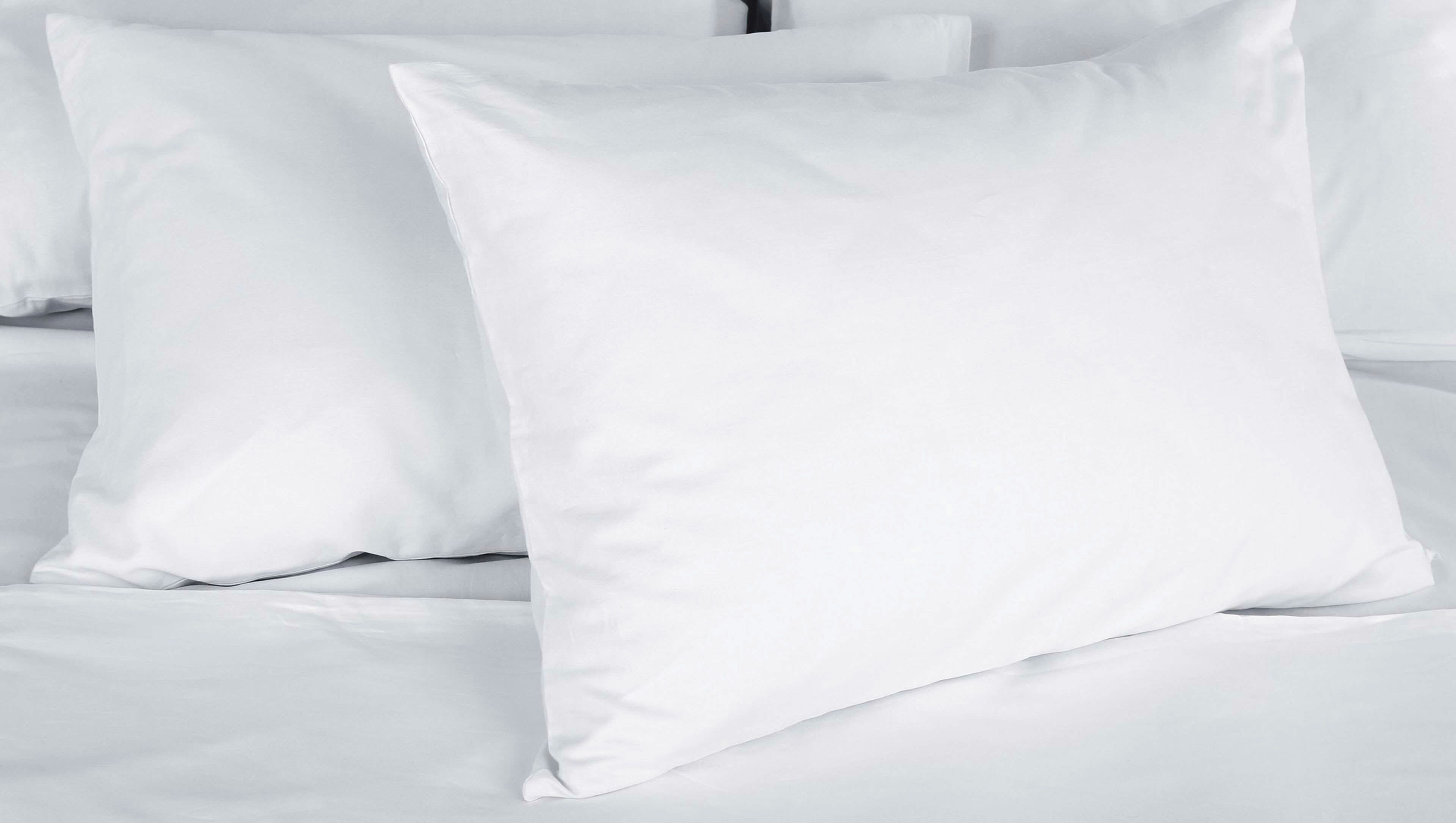 Una cama con ropa de cama blanca y almohadas.