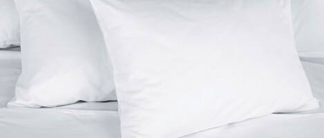 Una cama con ropa de cama blanca y almohadas.