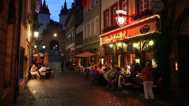 A cobblestone street with outdoor seating at a restaurant named "Hair Neufel". - Hotel & Restaurant Hackteufel (Heidelberg)