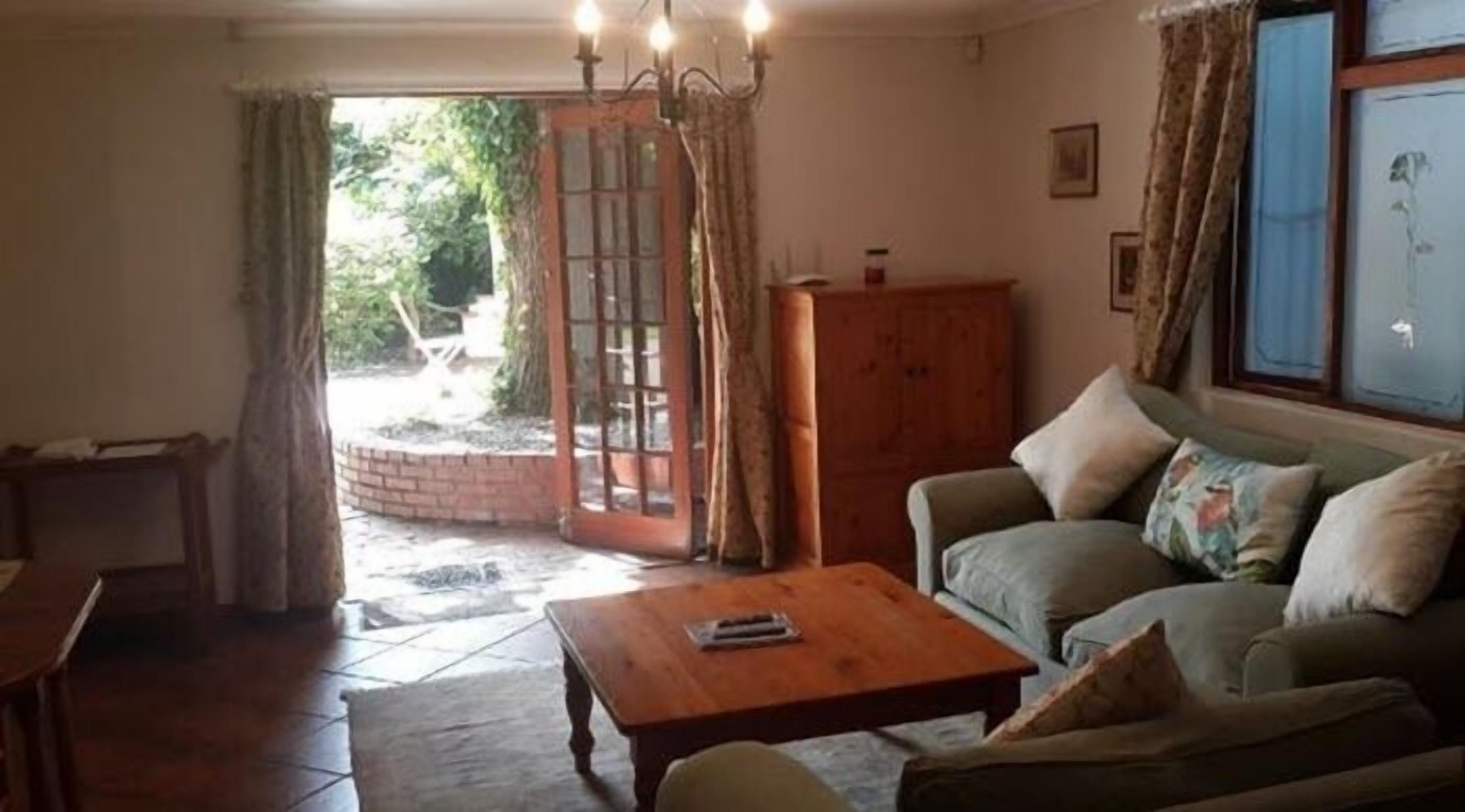 A living room with a sofa, a wooden coffee table, and a view of a garden through a glass door.