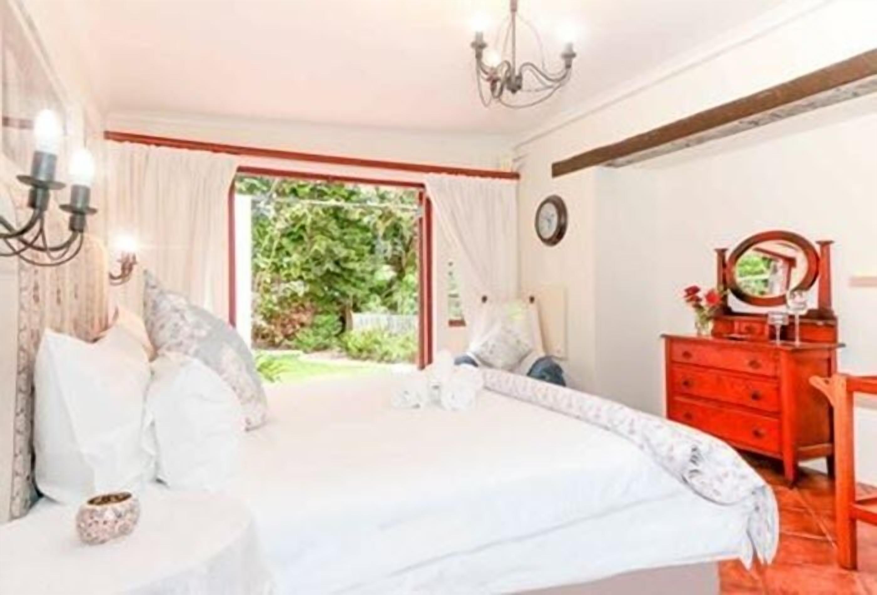 Une chambre à coucher avec un lit, une commode, un miroir et une fenêtre avec des rideaux.