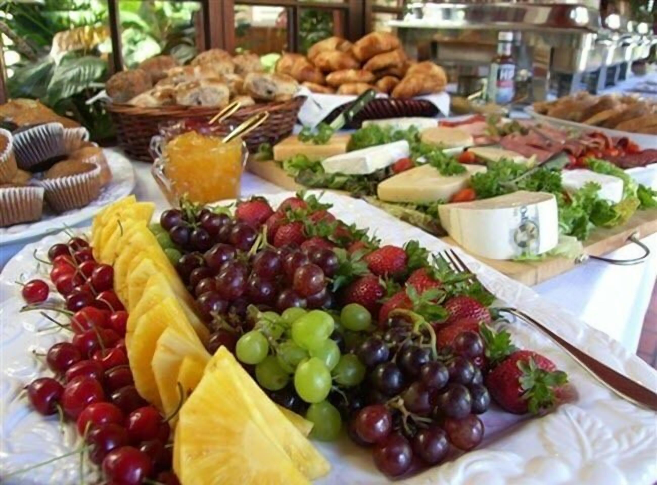 Un buffet proposant une variété de plats, notamment des fruits, des fromages et des pâtisseries.