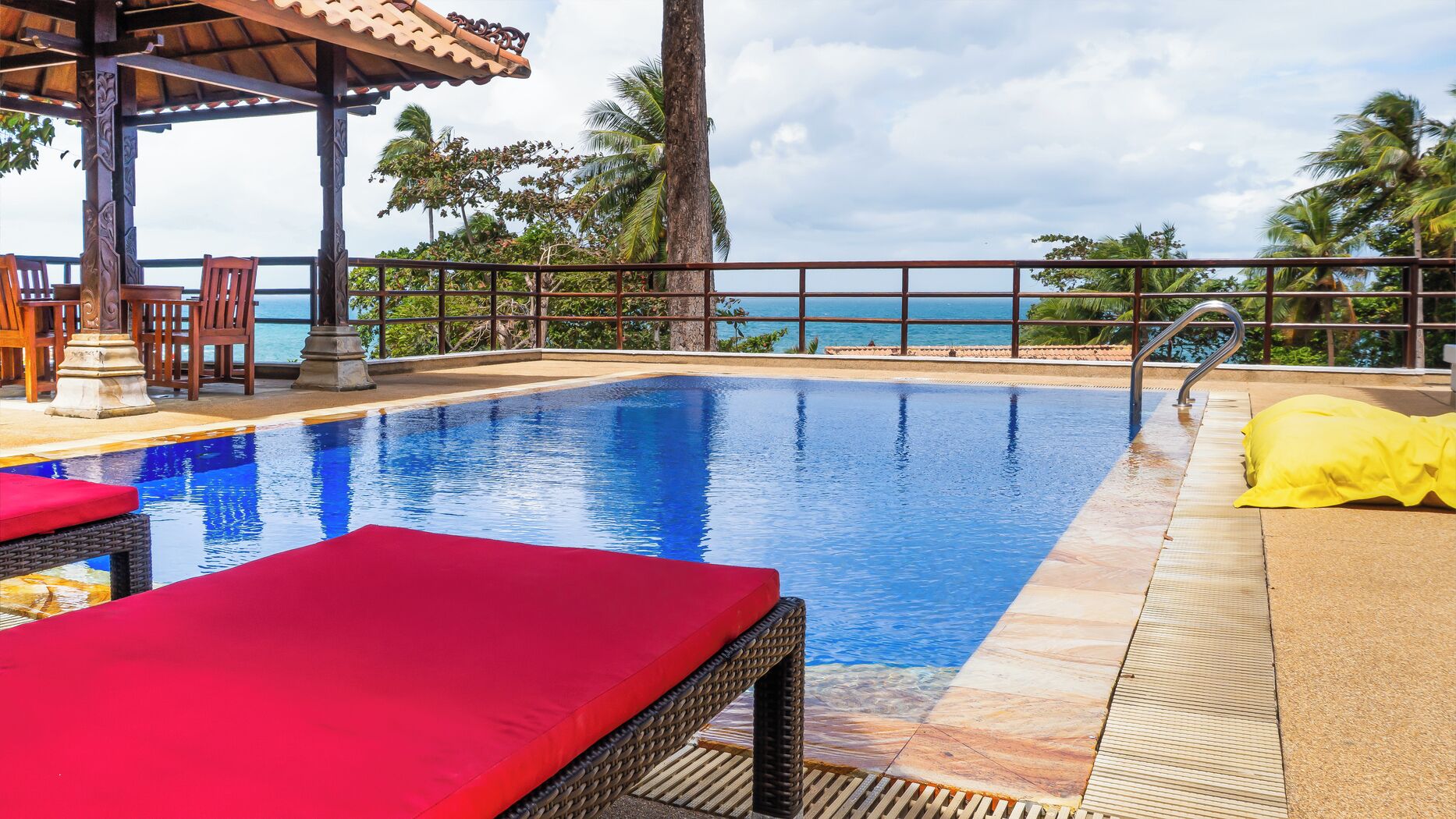 A swimming pool with lounge chairs and a view of the ocean.