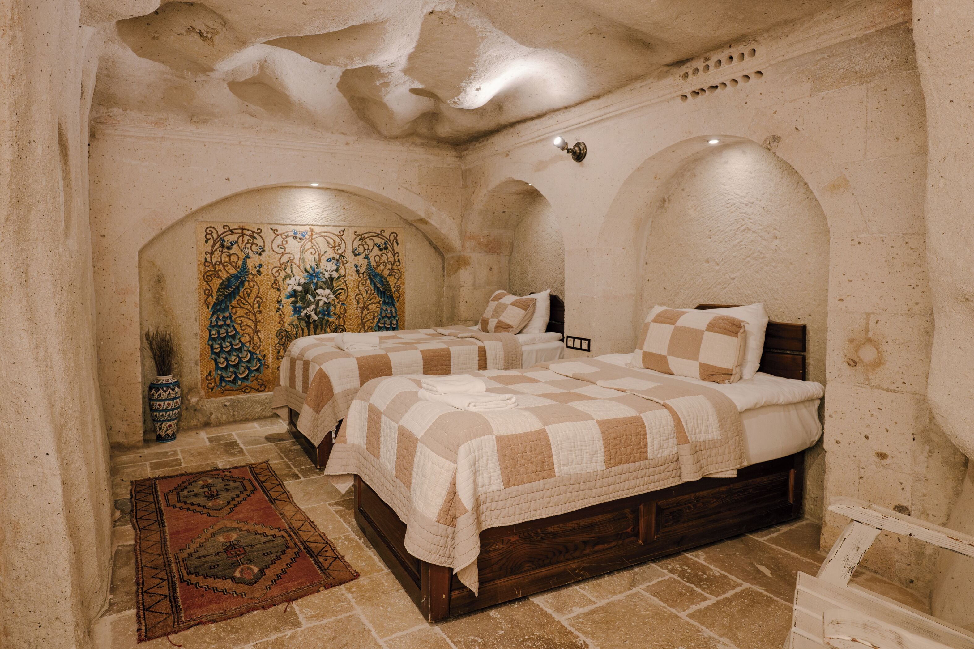A bedroom with two beds, a decorative wall, and a tiled floor.