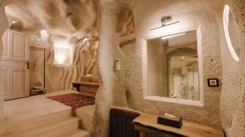A room with a stone wall, a wooden bench, a mirror, and a wooden door.