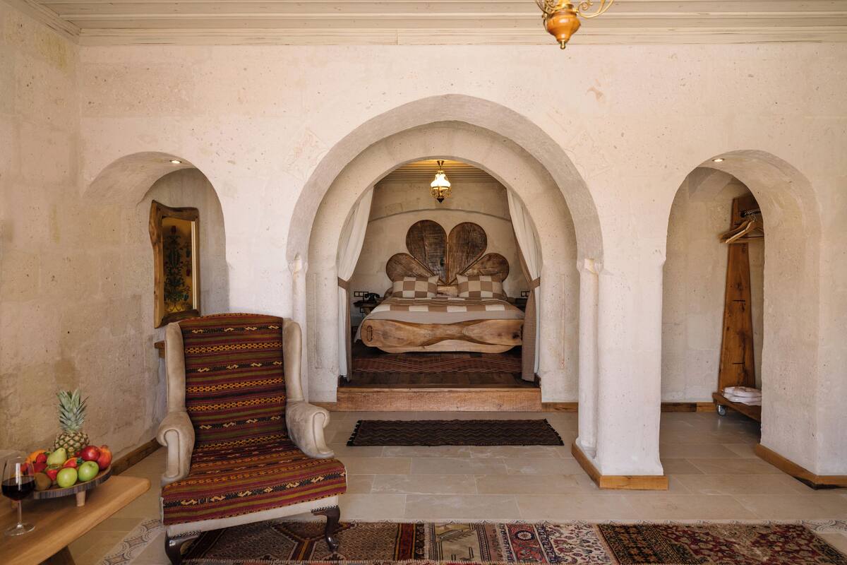 Un dormitorio con una cama grande, un arco de entrada, una silla y un frutero.