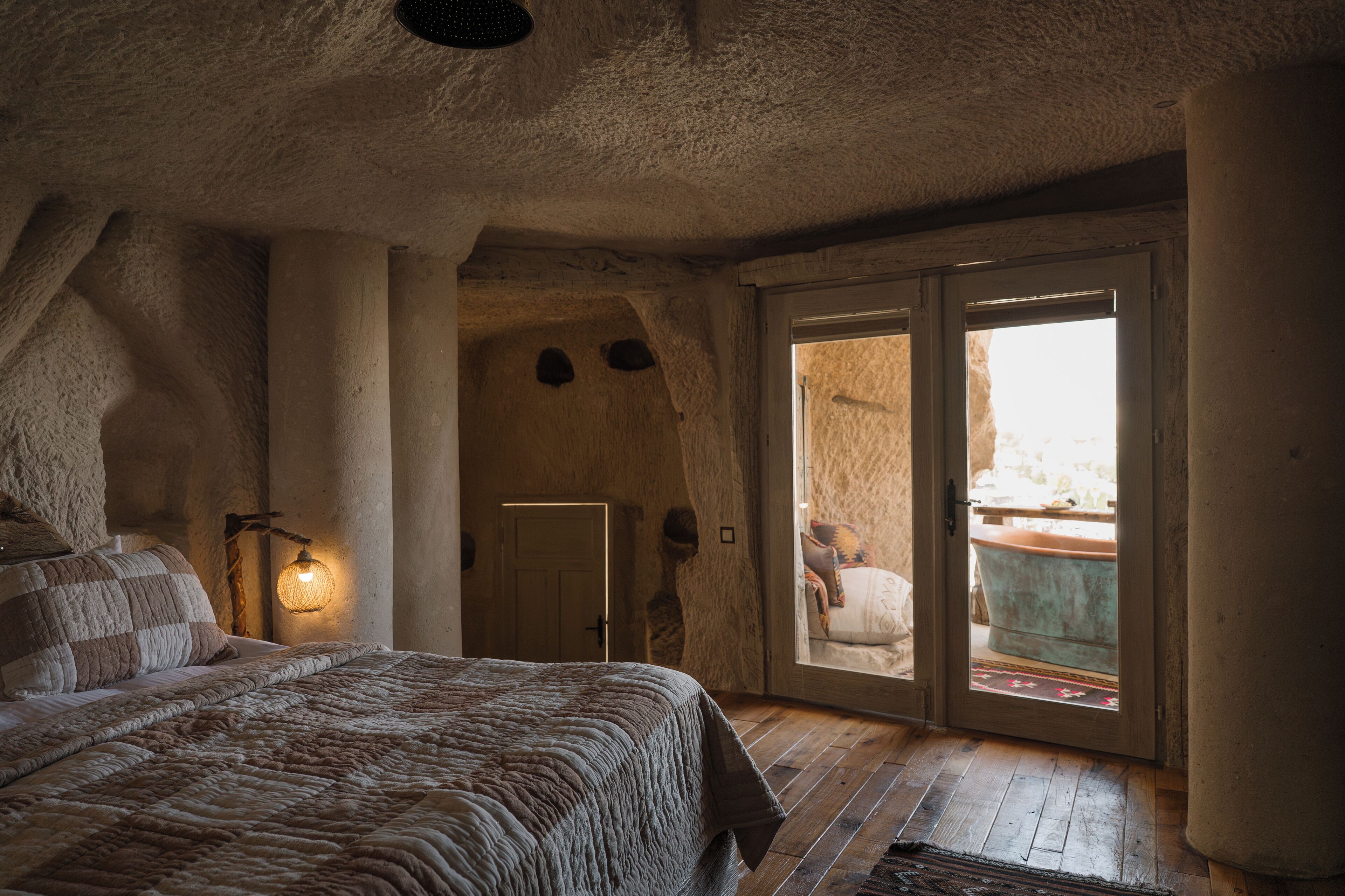 Un dormitorio rústico con una cama grande, una pared de piedra y vistas a través de un ventanal.
