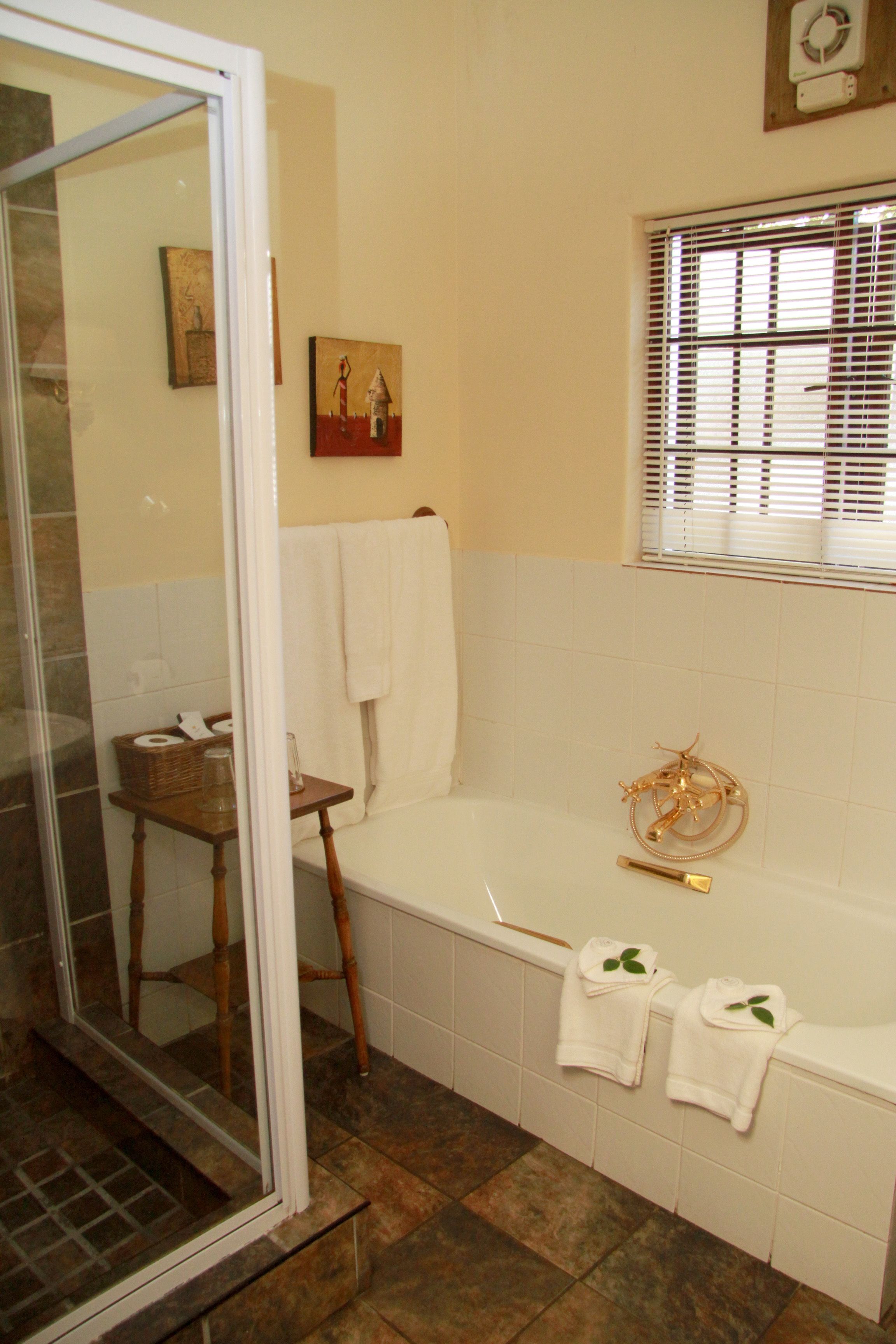 A bathroom with a bathtub, a shower area, and a window with blinds.