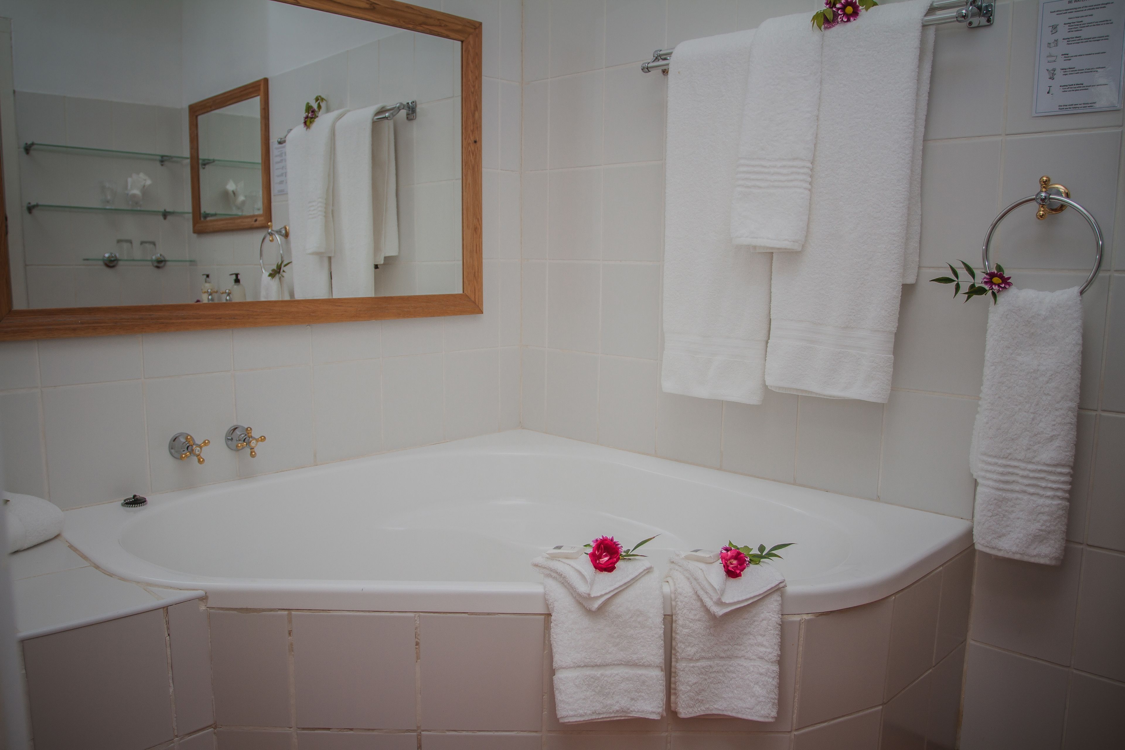 Un baño con bañera, espejo y varias toallas blancas.