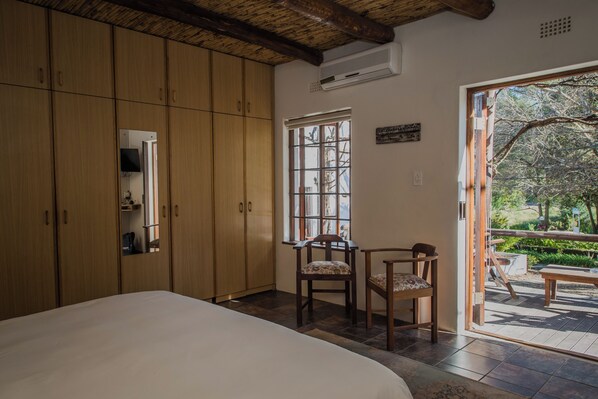 Un dormitorio con una cama grande, un armario de madera, una silla y una mesa. Hay una ventana con vistas al exterior.
