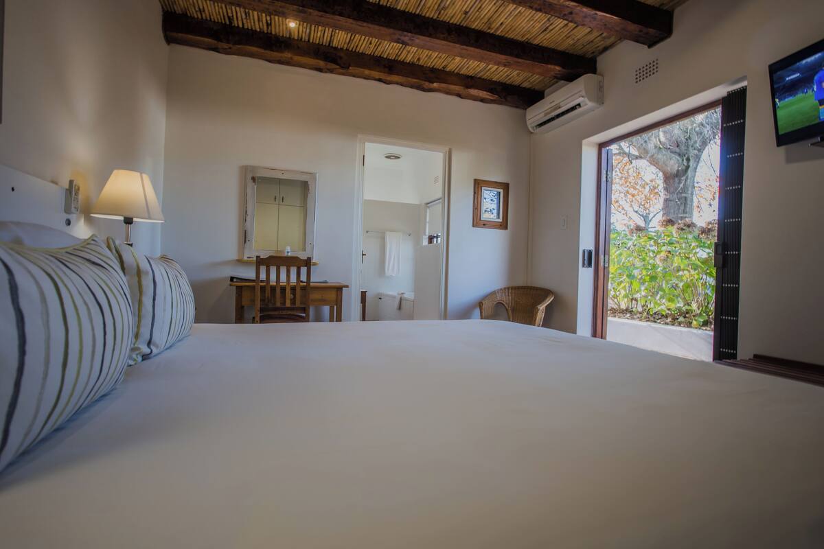 Un dormitorio con una cama grande, un escritorio, una silla, un espejo y un televisor.