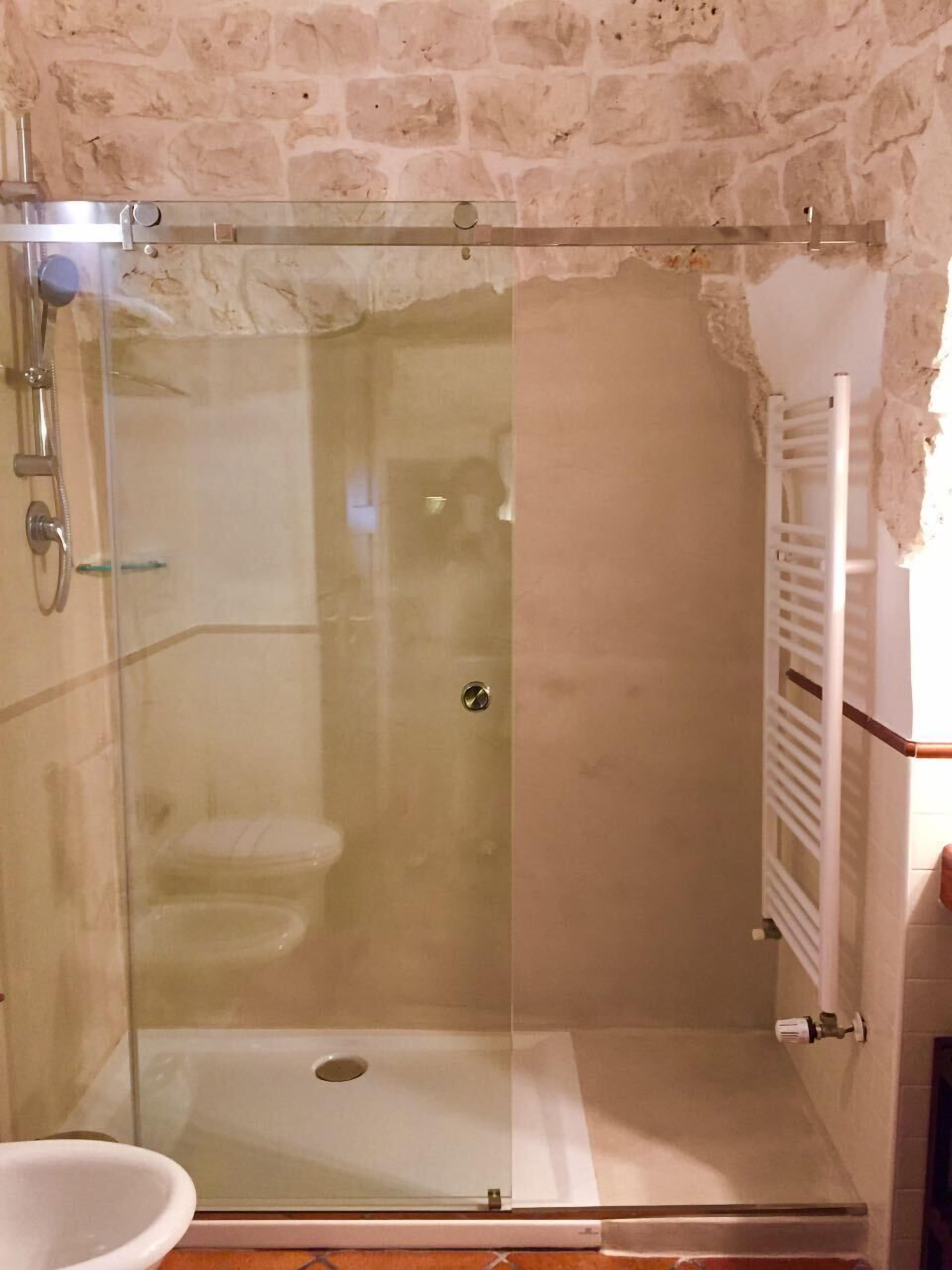 A glass-enclosed shower area with a white sink and a towel rack.