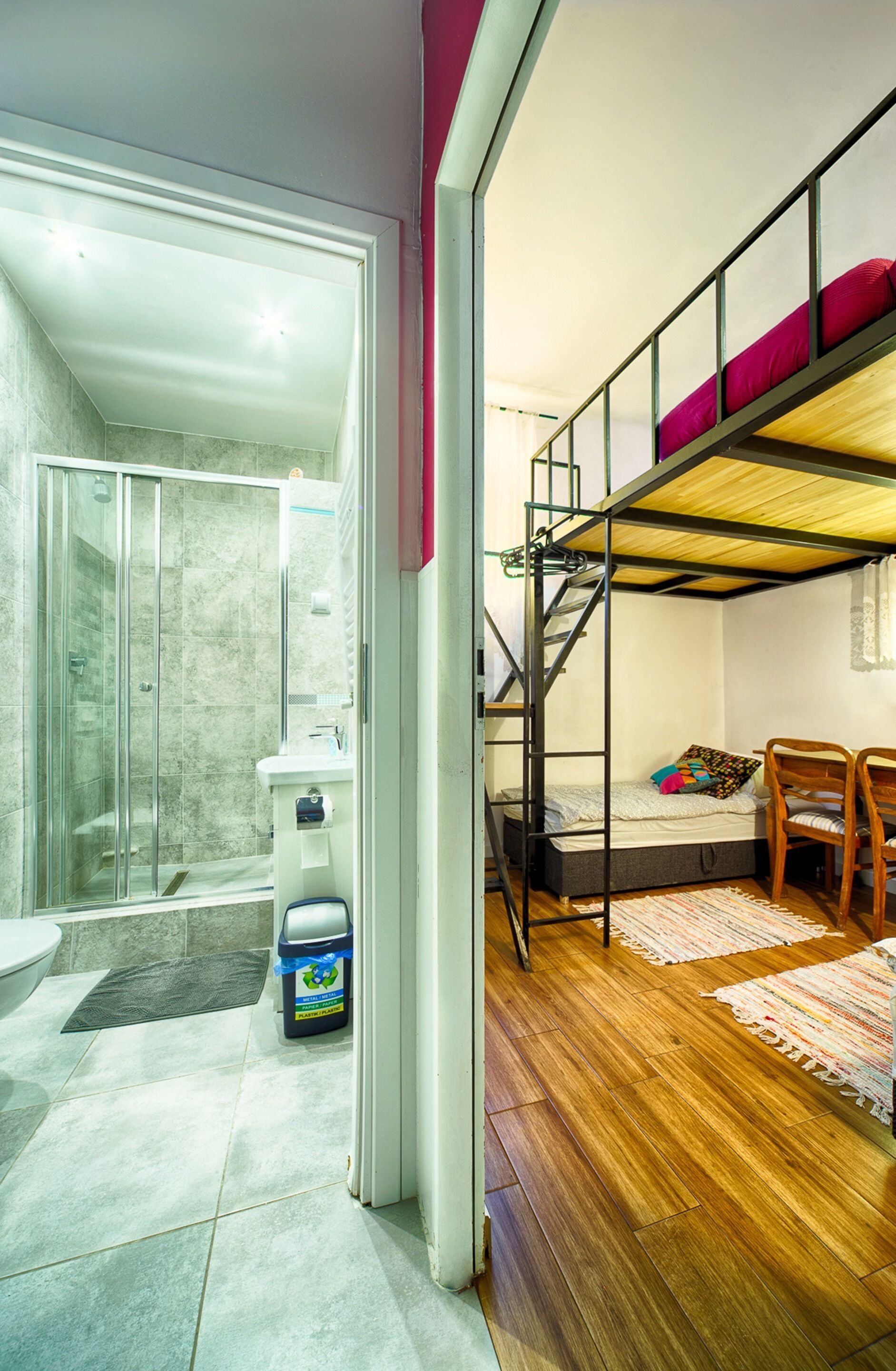 Une petite chambre comprenant un lit superposé, une douche et un petit espace bureau.