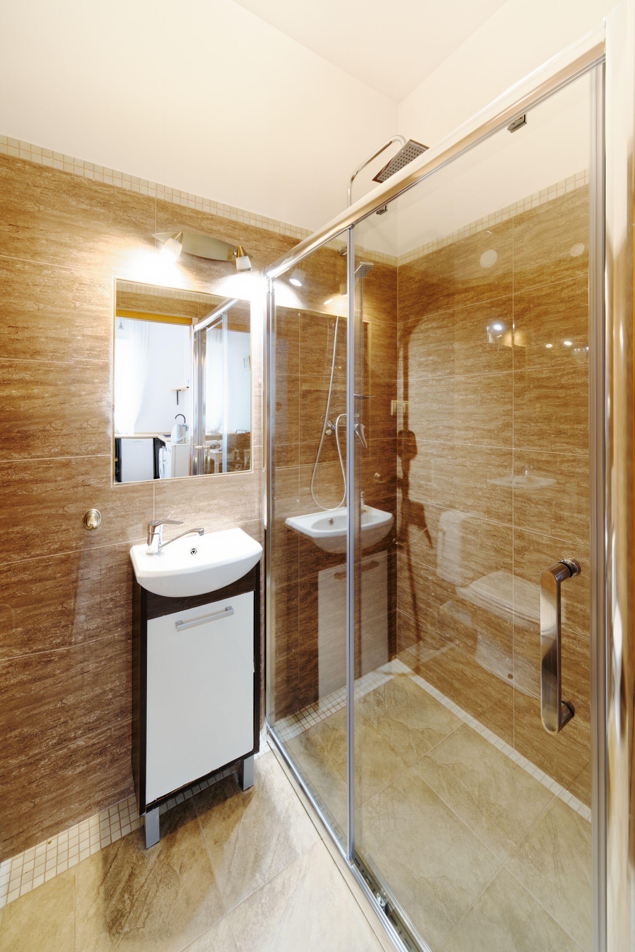 Une salle de bain moderne dotée d’une douche à parois de verre, de deux lavabos et d’un grand miroir.