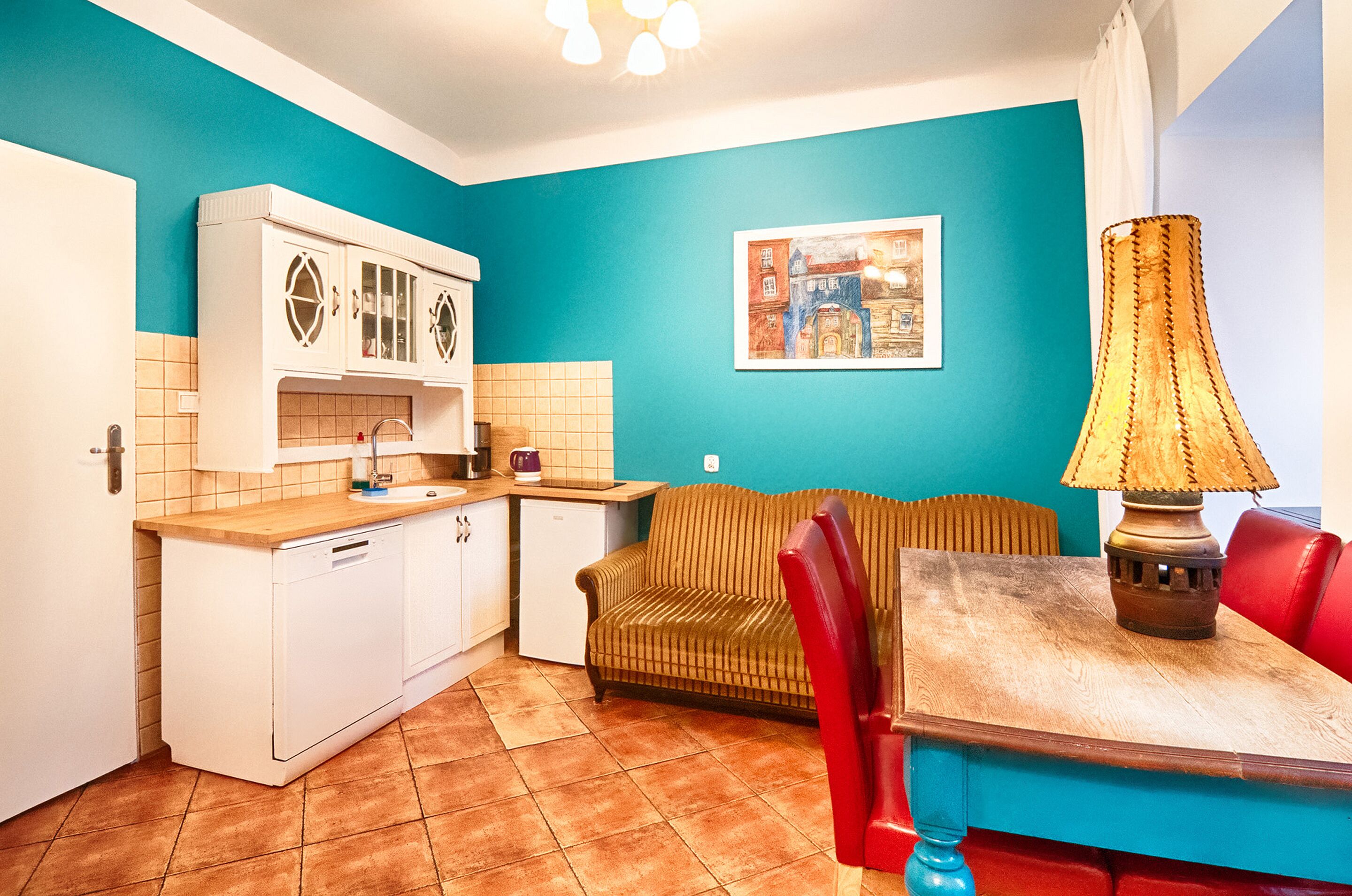 Een kleine keuken met een vaatwasser, een kleine koelkast, een houten aanrechtblad en een wand in de kleur teal.
