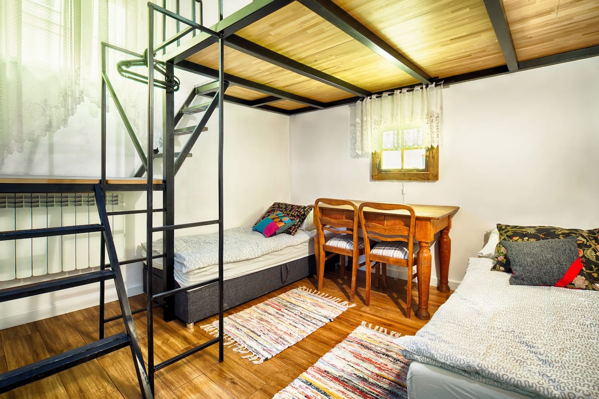 Une petite pièce comprenant un lit superposé, un bureau et une chaise.
