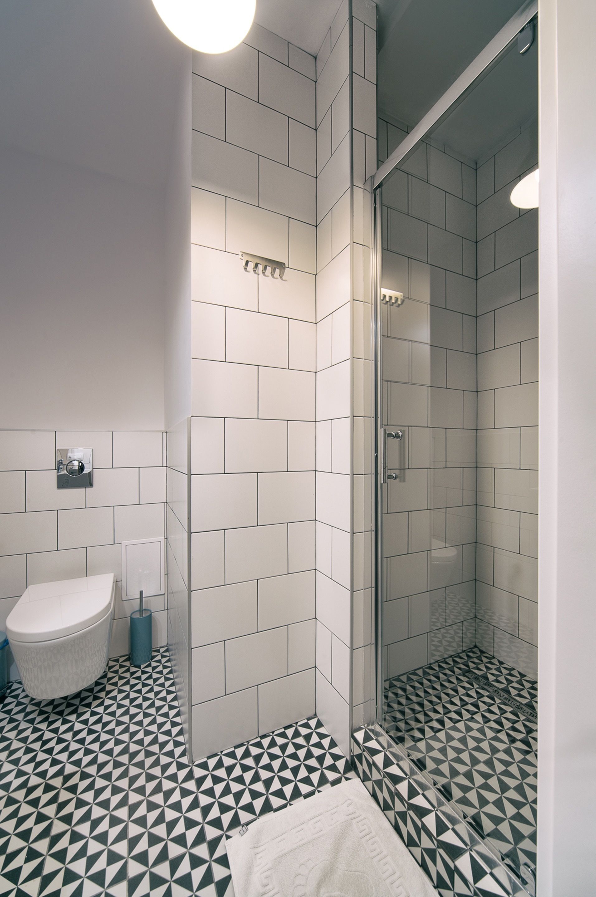 A bathroom with a white toilet, a glass shower enclosure, and a patterned floor.
