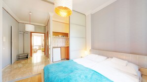 A hotel room with a large bed, a kitchenette, and a bathroom.