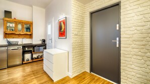A modern kitchen with stainless steel appliances, a white cabinet, and a brick wall.