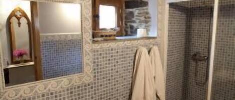 A bathroom with a sink, mirror, and shower.