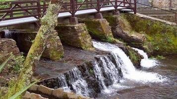 A waterfall with a wooden bridge and a stone wall.