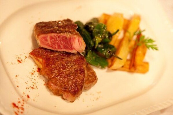 A plate with a steak, fries, and greens.
