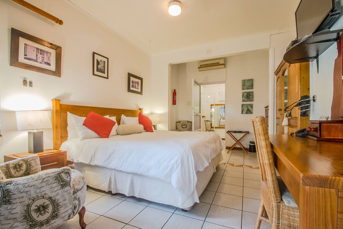 A hotel room with a large bed, a wooden headboard, a desk with a chair, and a television.