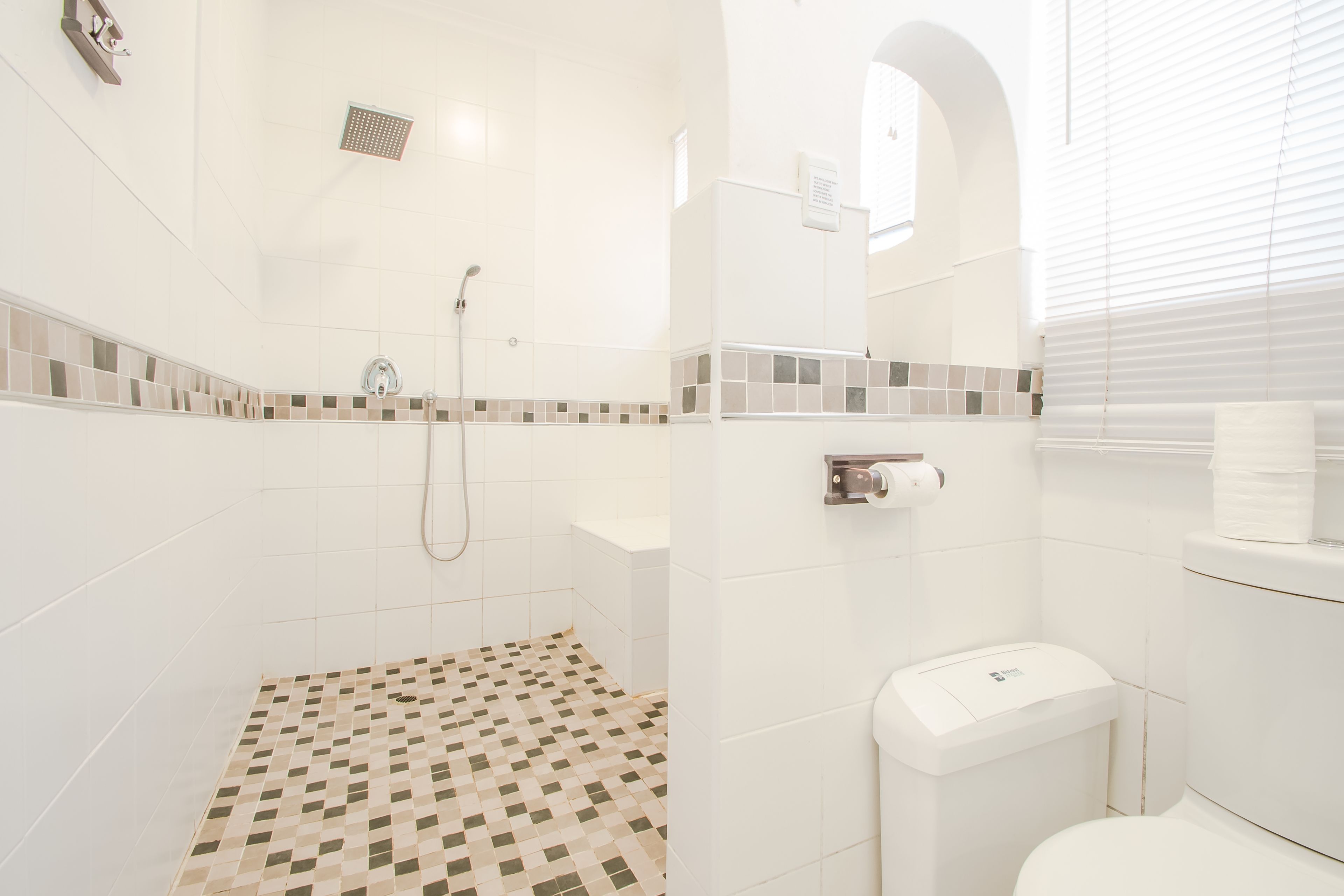 A bathroom with a shower, toilet, and tiled floor.