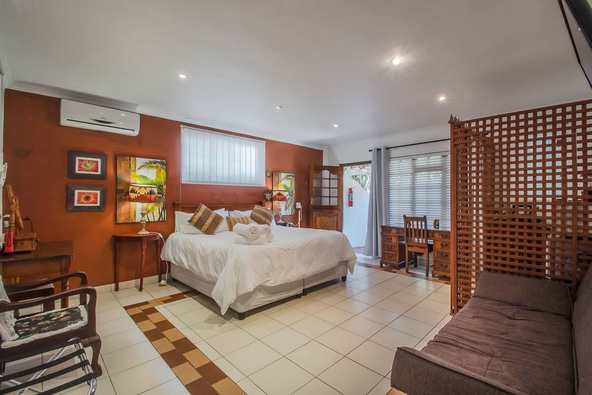 A hotel room with a large bed, a wooden partition, a desk, and a chair.