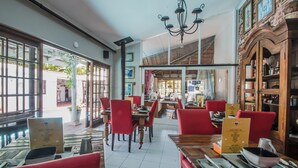 A restaurant with red chairs, wooden tables, and a chandelier. - HoneyPot Guesthouse (Umhlanga)