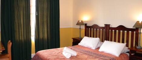 A neatly made bed with a patterned bedspread, two bedside lamps, and a wooden headboard.