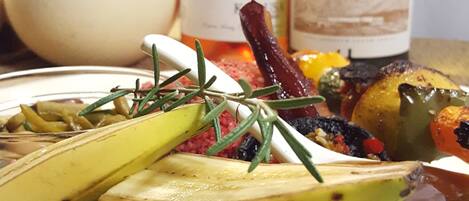 A plate of food with a slice of meatloaf topped with cheese and vegetables, a bottle of wine, and a roasted egg in the background.