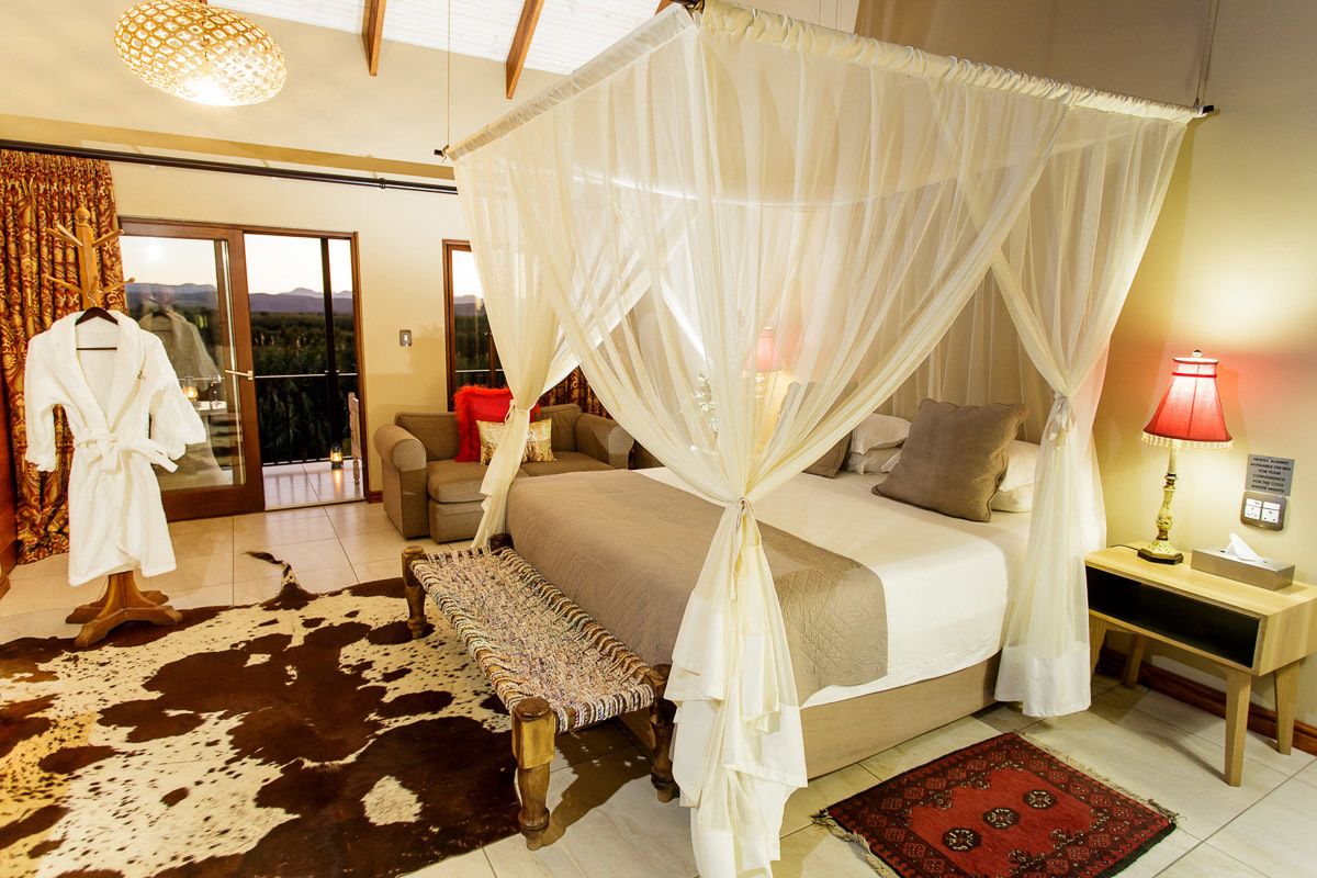 Un dormitorio con cama con dosel, un banco, alfombra de cuero de vaca y vistas a través de una puerta corredera.