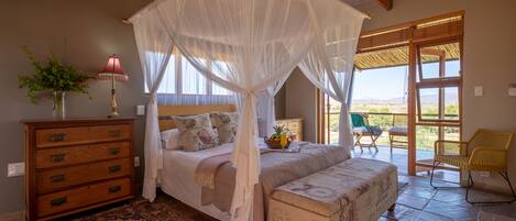 A bedroom with a canopy bed, a wooden dresser, a patterned rug, and a view of the outdoors through a glass door.