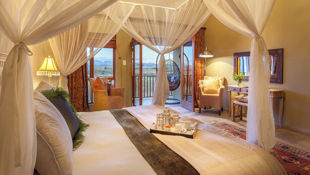 A spacious bedroom with a large bed, a tray with tea set, and a view of the outdoors. - De Zeekoe Guest Farm (Oudtshoorn)