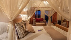 A bedroom with a canopy bed, a sofa, and a view of the night sky. - De Zeekoe Guest Farm (Oudtshoorn)