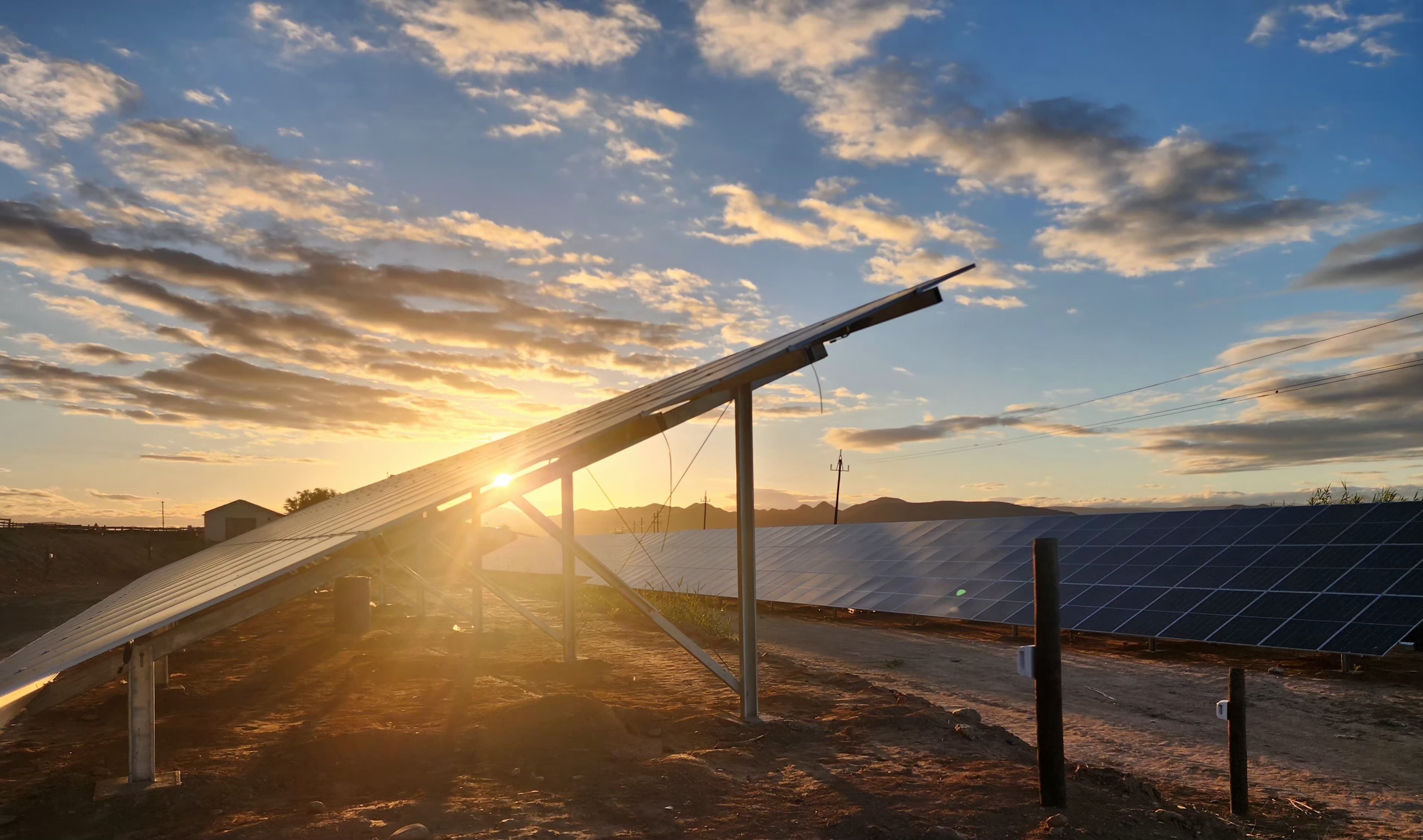 Instalación de paneles solares, cielo despejado y montañas al fondo.