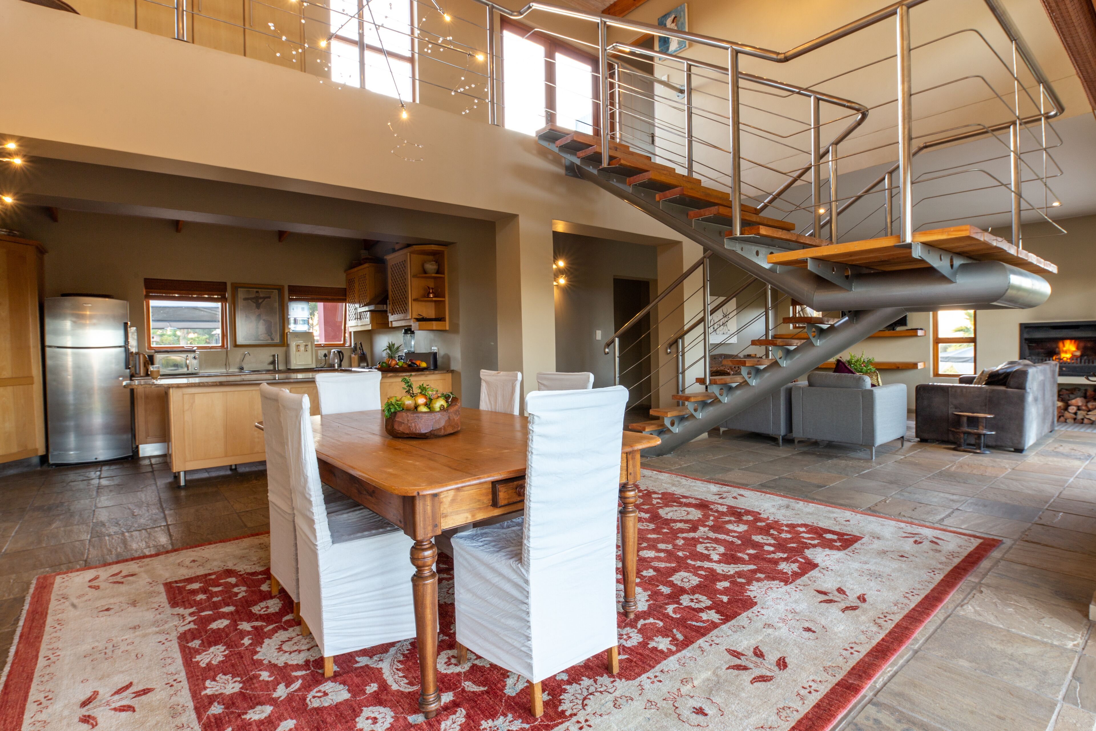 A spacious kitchen with a dining area, a staircase, and a fireplace.