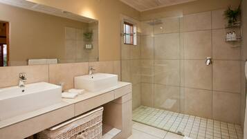 Un baño moderno con dos lavamanos, una cabina de ducha de vidrio y un espejo sobre el lavamanos.