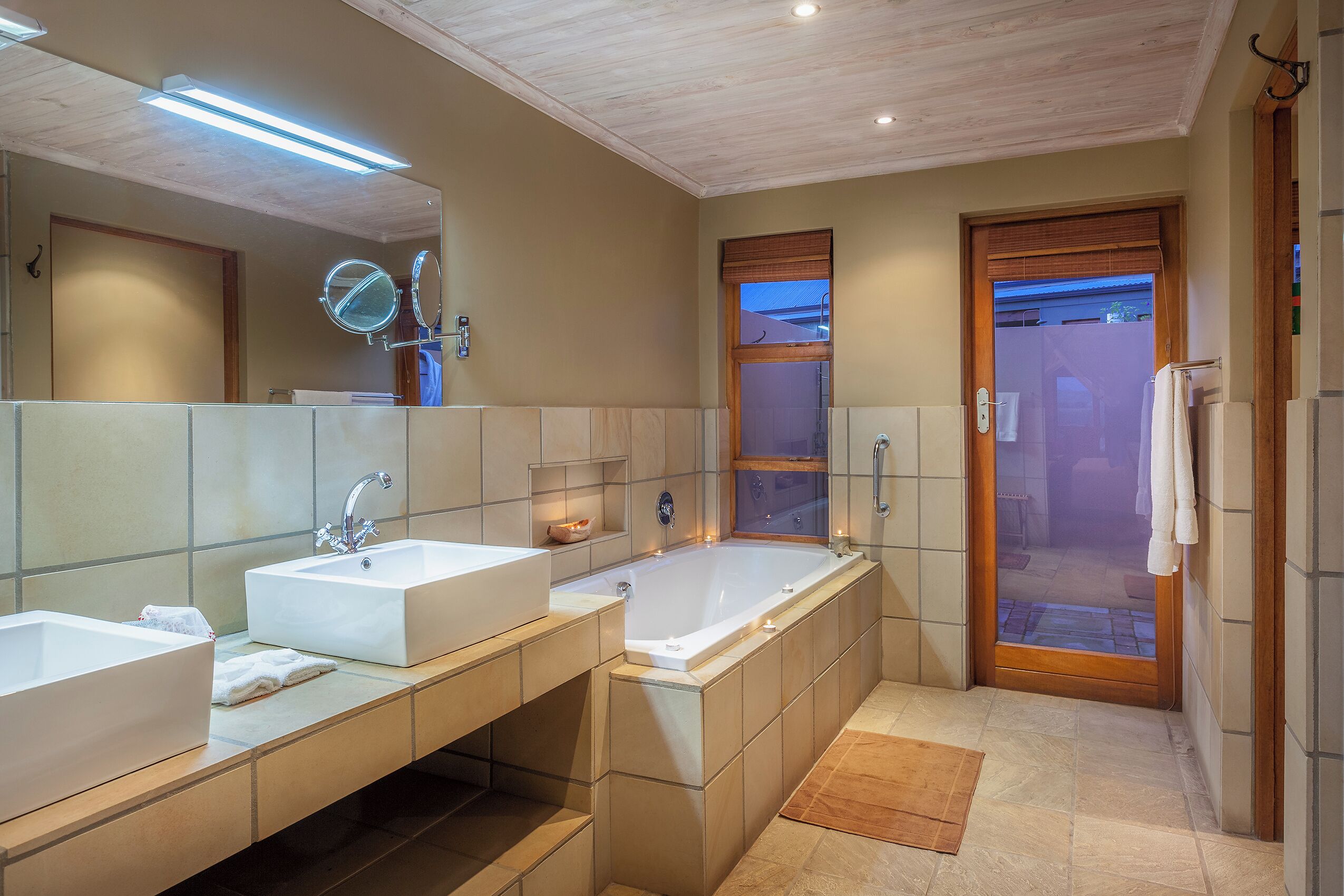 Un baño moderno con dos lavamanos, una bañera amplia y una zona de ducha con mampara de vidrio.